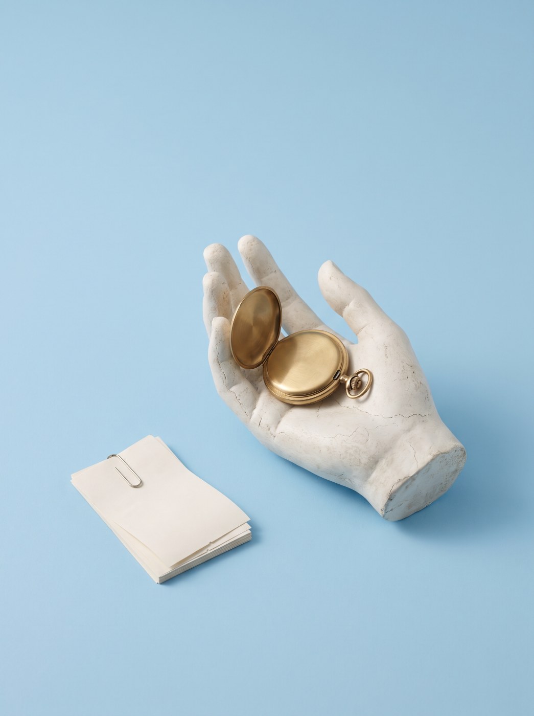 Automated invoice data extraction: plaster hand holding a pocket watch beside clipped receipts