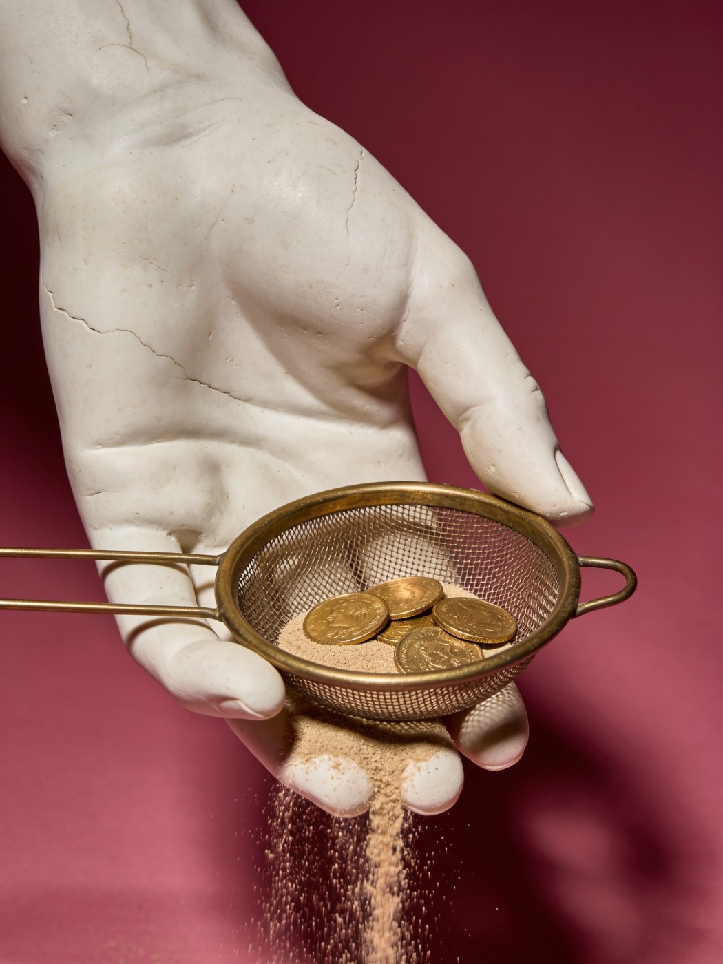 Google Ads search term and negative keyword management: plaster hand with a sieve keeping the coins and letting sand fall