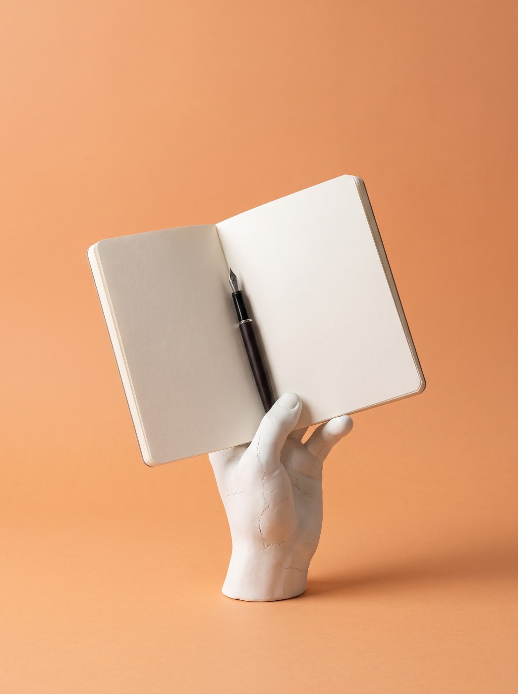 SEO content writing: plaster hand holding an open notebook and fountain pen