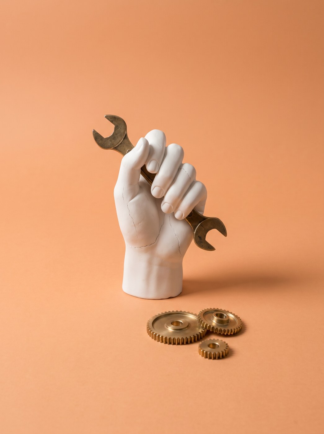 Technical SEO audit and site fixes: plaster hand gripping a brass wrench beside gears